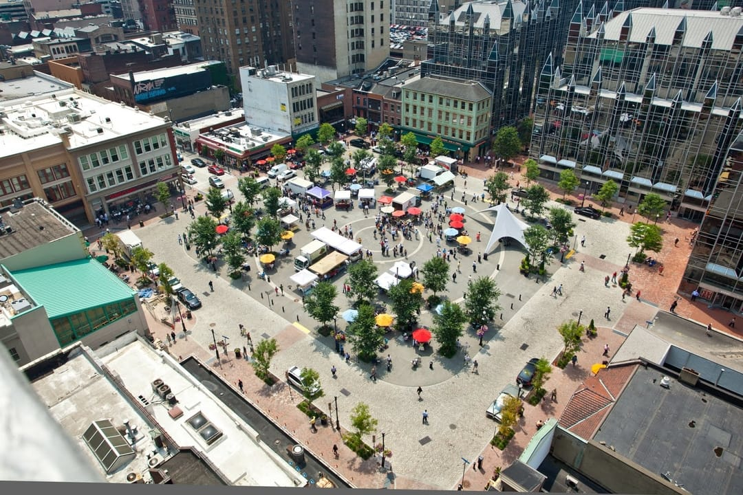 A town square full of people and stalls on a market day